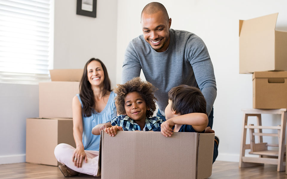 Happy multiethnic family playing with moving boxes while packing to move into their new home